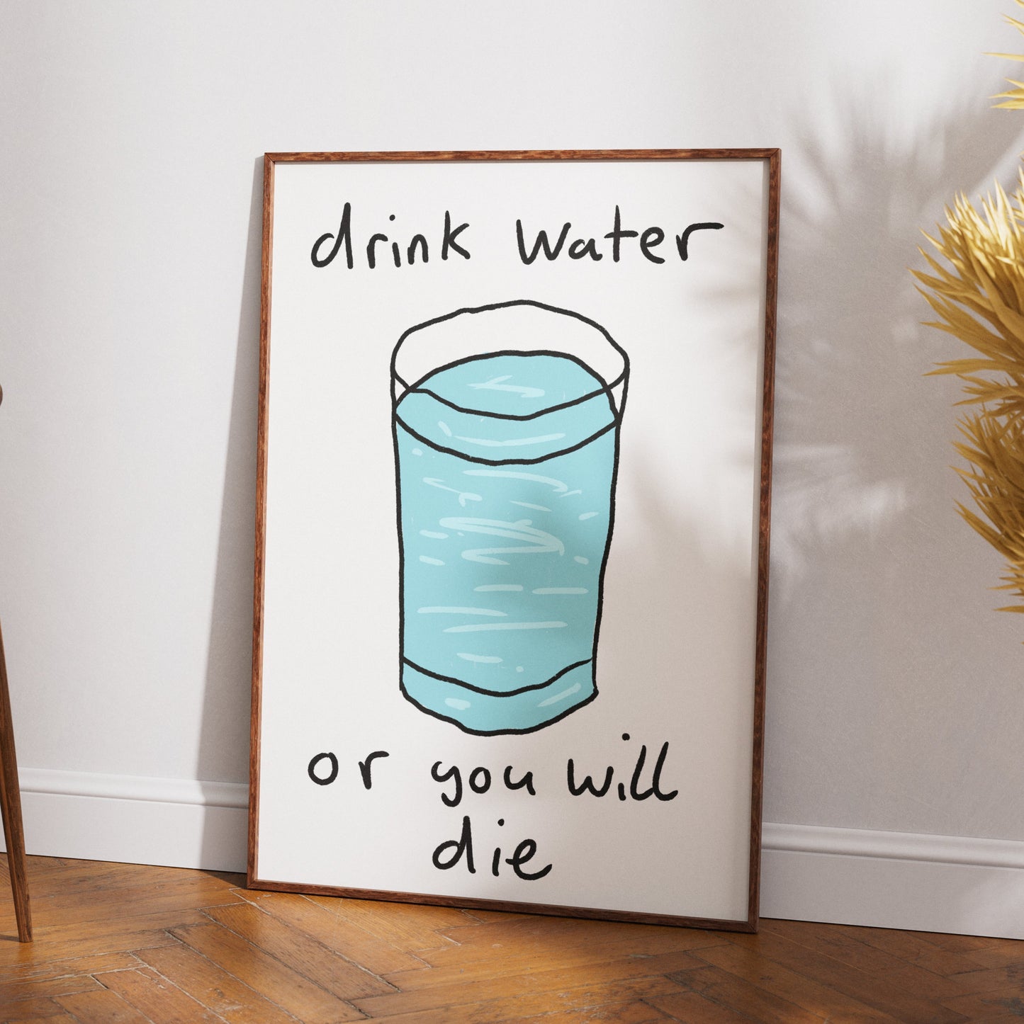 Framed poster with a glass of water and text 'drink water or you will die' on a wall.